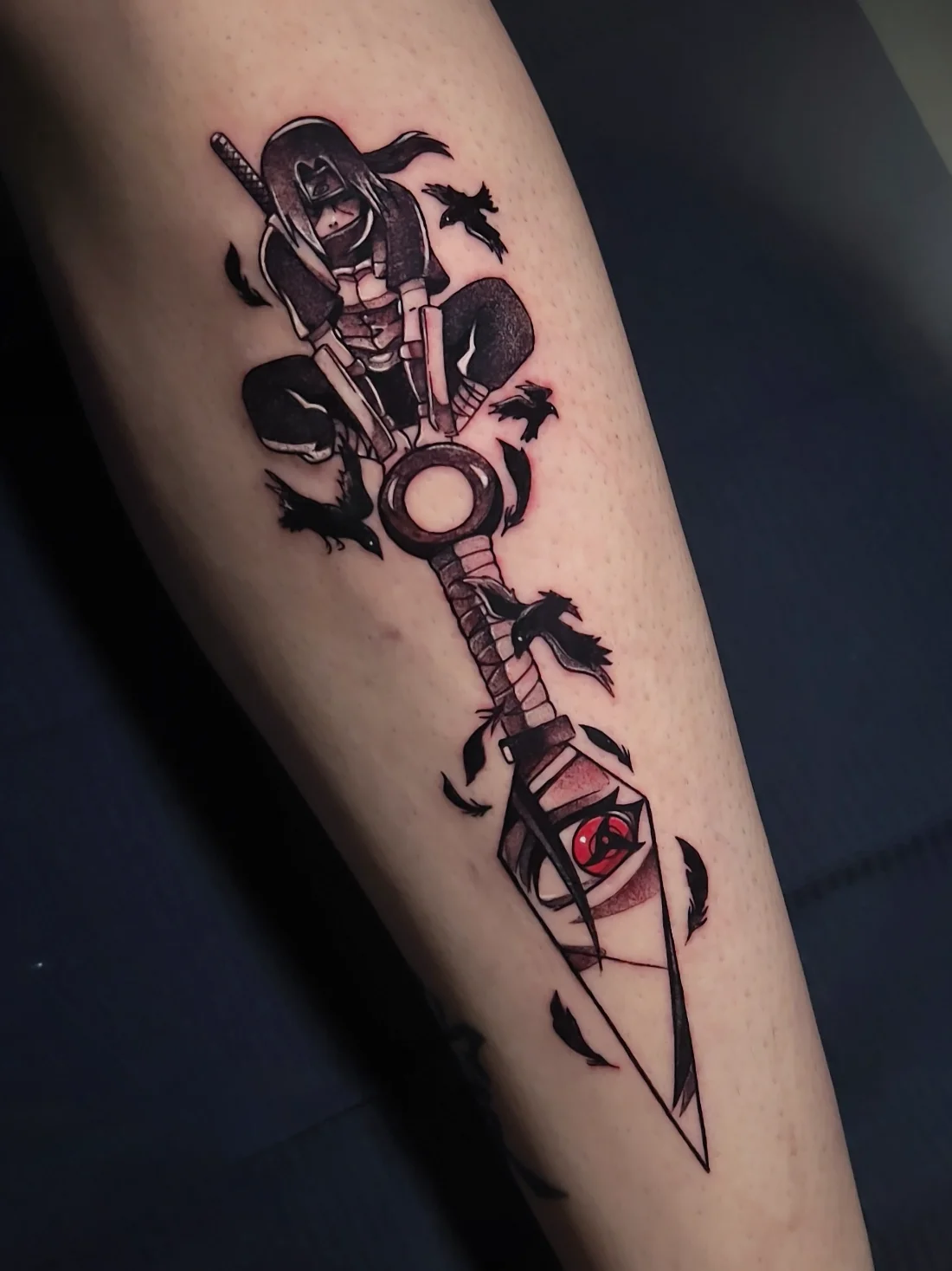 Tatuagem blackwork do Itachi de Naruto com corvos e sharingan feita pela Jess Zanatta