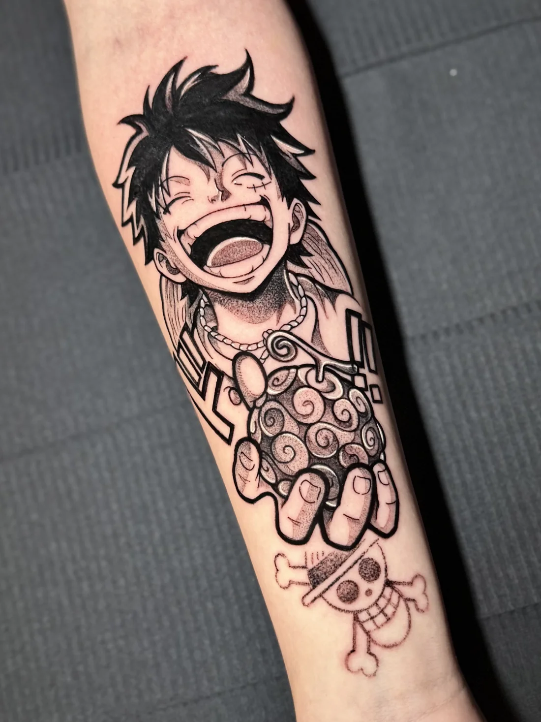 Tatuagem blackwork do Luffy rindo com gomu gomu de One Piece feita pela Jess Zanatta