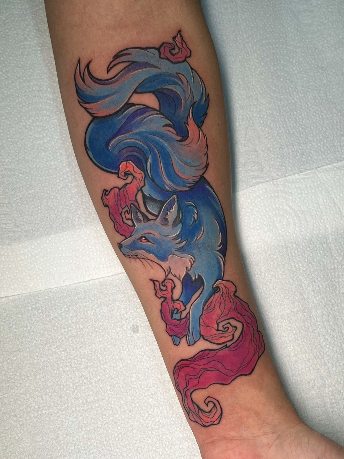 Tatuagem autoral de raposa em aquarela azul e rosa feita pela Jess Zanatta